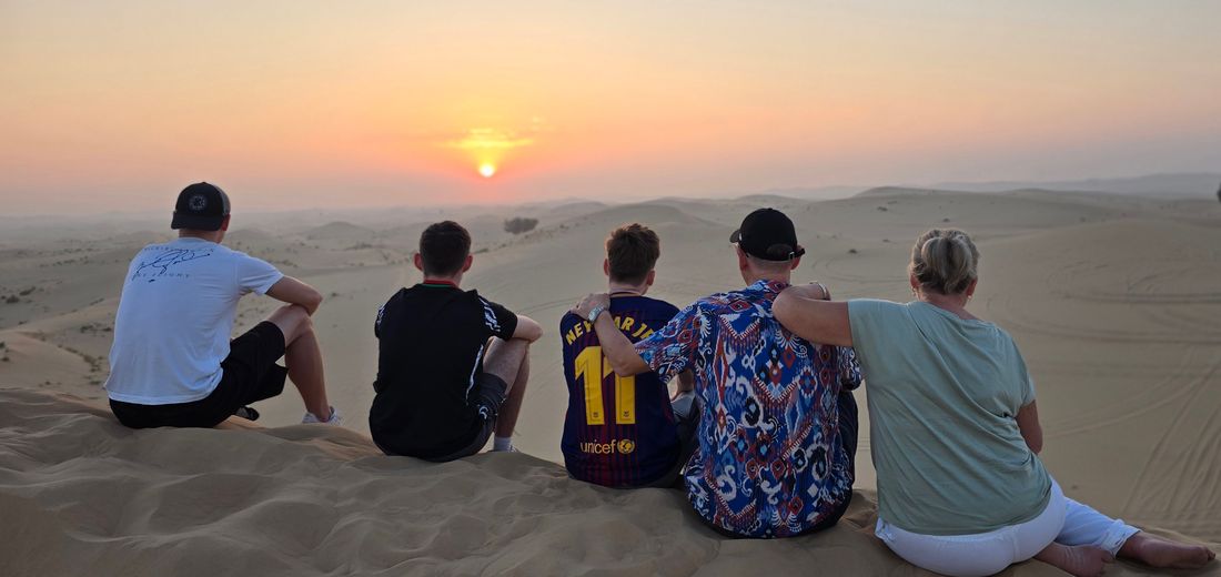 The family watching the sunset over desert dunes